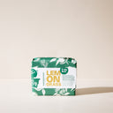 A bar of Lemongrass soap wrapped in green packaging on a light background