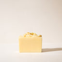 A pale yellow bar soap without it's packaging on a light background