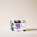 A bar of Night Violet soap with its packaging on a light background