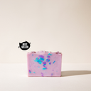 A light pink soap bar with blue and purple speck without it's packaging on a light background and a best seller tag