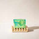 A concrete soap dish with channels for draining with a handmade soap on it.