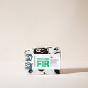 A bar of Frosted Fir Soap with wrapping paper on a light background