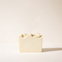 A light beige bar of Oatmeal Chamomile soap without it's packaging on a light background
